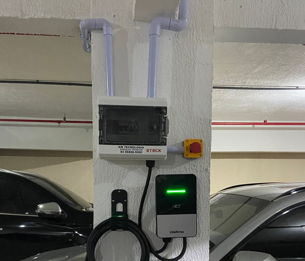 Instalação real da KM Tecnologia em garagem de condomínio: eletrodutos, quadro de proteção, botoeira de emergência e wallbox Intelbras